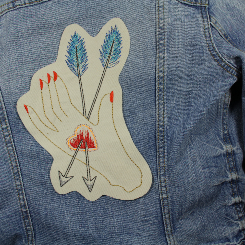 Stickerei auf einer Jeansjacke als großer Rückenpatch zum aufbügeln Hand mit Herz und Pfeil