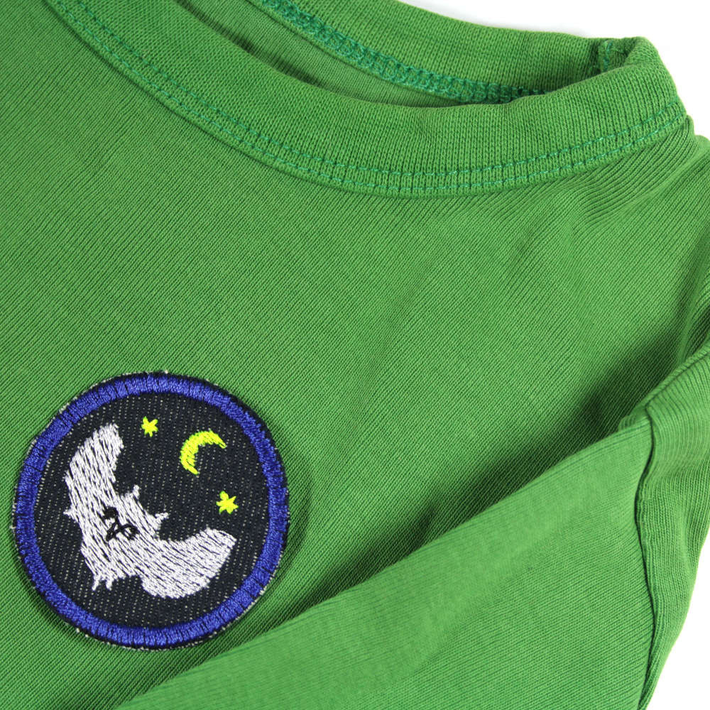 Rundes Bügelbild mit Eule als Jeansflicken auf grünem Sweater in Kindergröße.
