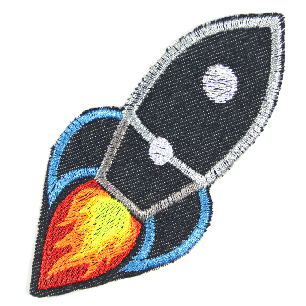 Rakete aus dunkelblauem Bio Jeansstoff mit weiß, grau und blau gestickt sowie einem Feuerstrahl in neongelb, neonorange und neonrot