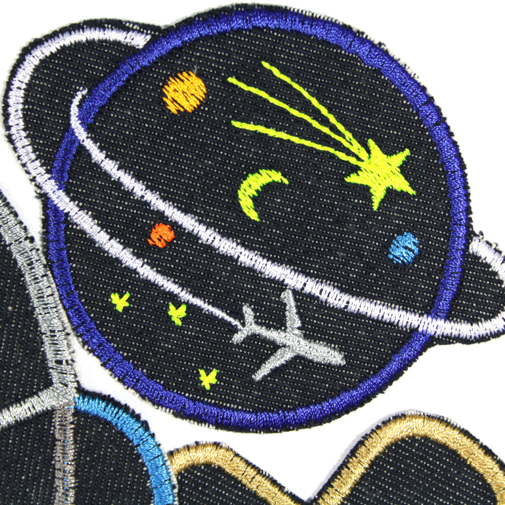 Detailbild des runden Space Flickens, ein in dunkelblauen Nachhimmel gehüllter Planet mit Sternschnuppe und Mondsichel, der von einem Flugzeug umkreist wird