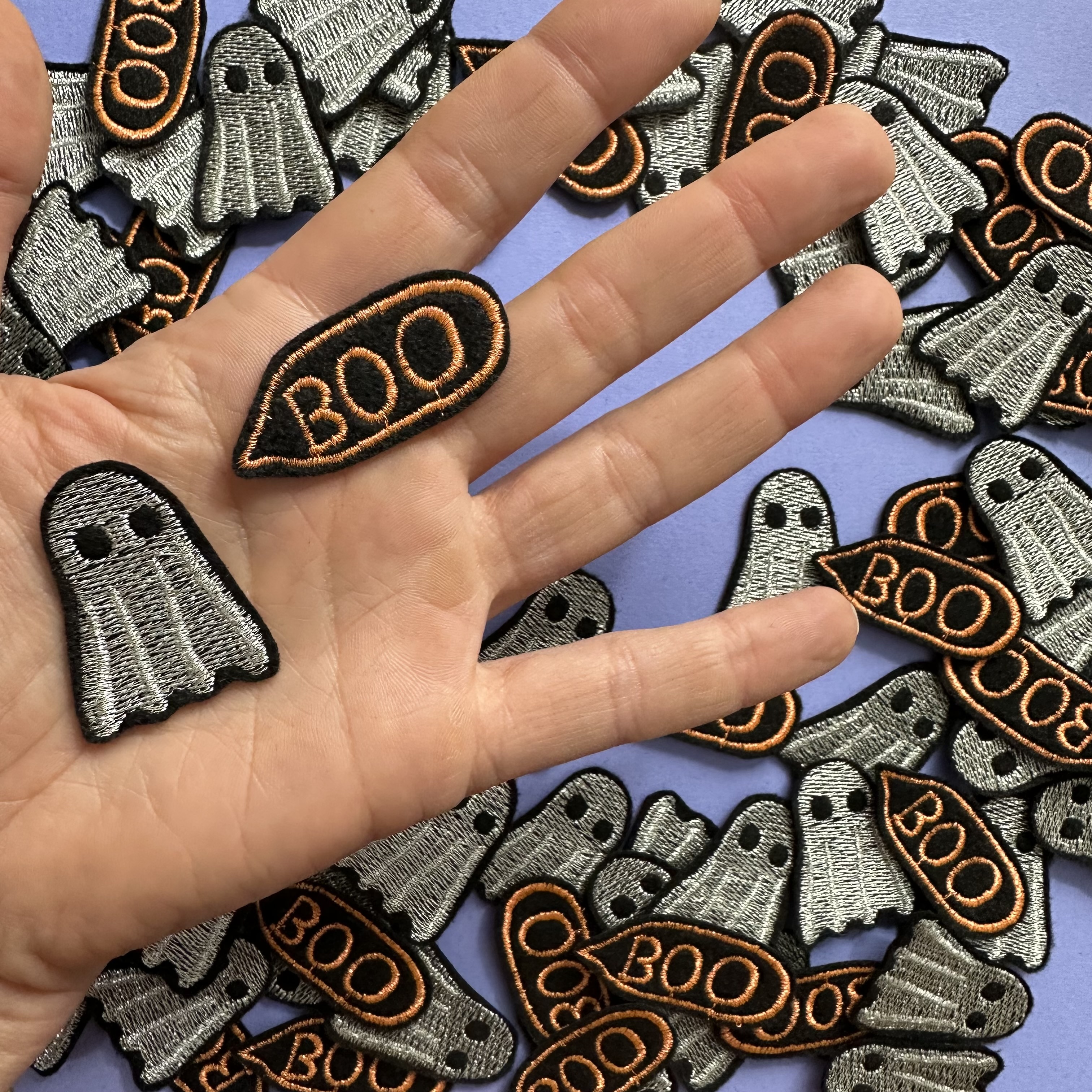 2 kleine glitzer Aufbügler Gespenst und SPrechblase Boo präsentiert auf einer Hand. Die Größe der kleinen Flicken entspricht einer halben Fingerlänge einer Frauenhand.