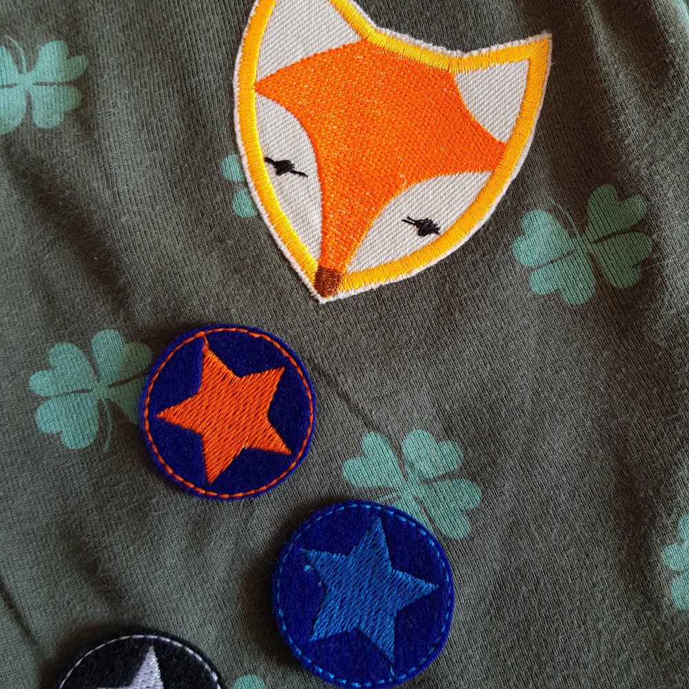 Fuchs Applikation und kleine runde Stern Bügelflicken auf einem T-Shirt mit Kleeblatt