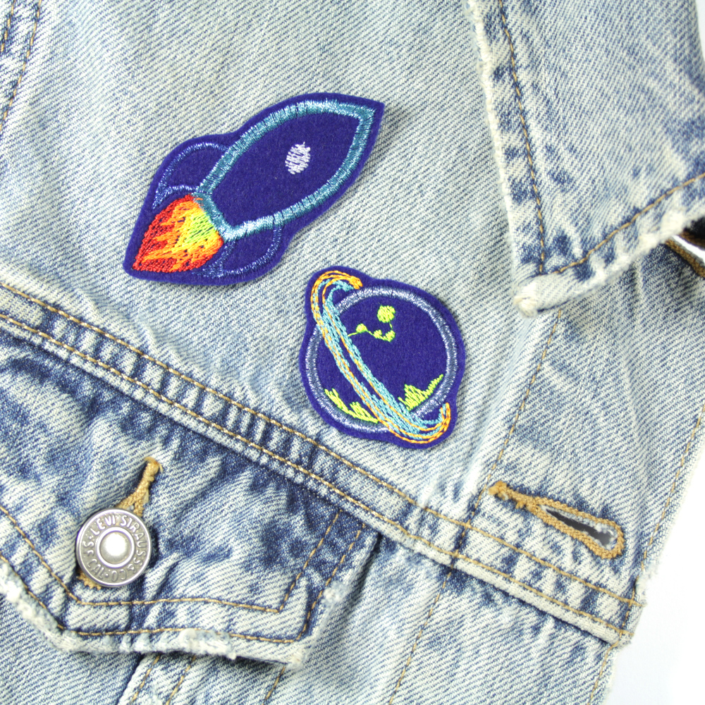 Rakete und Planet mit glitzer metallic und neon Garn als Accessoire auf einer Jeans Jacke